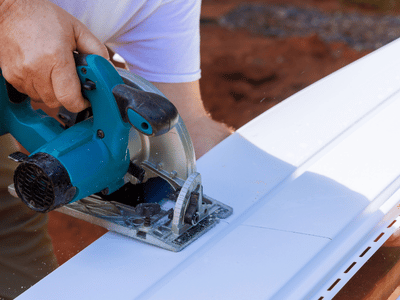 Professional contractor measures and cuts siding