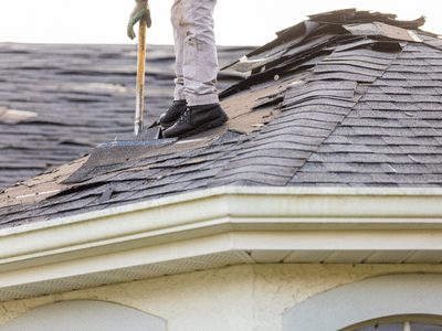 Professional roofer removing damaged and aging roof shingles