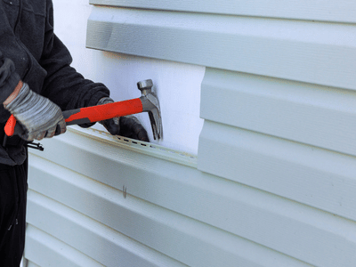 Siding contractor using hammer to remove damaged siding